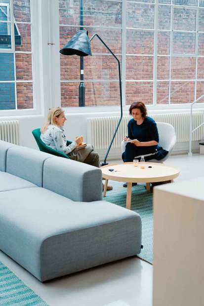 Two people talking over coffee in a bright lounge
