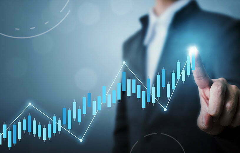 A hand reaching out to a rising blue candlestick chart in front of a businessperson